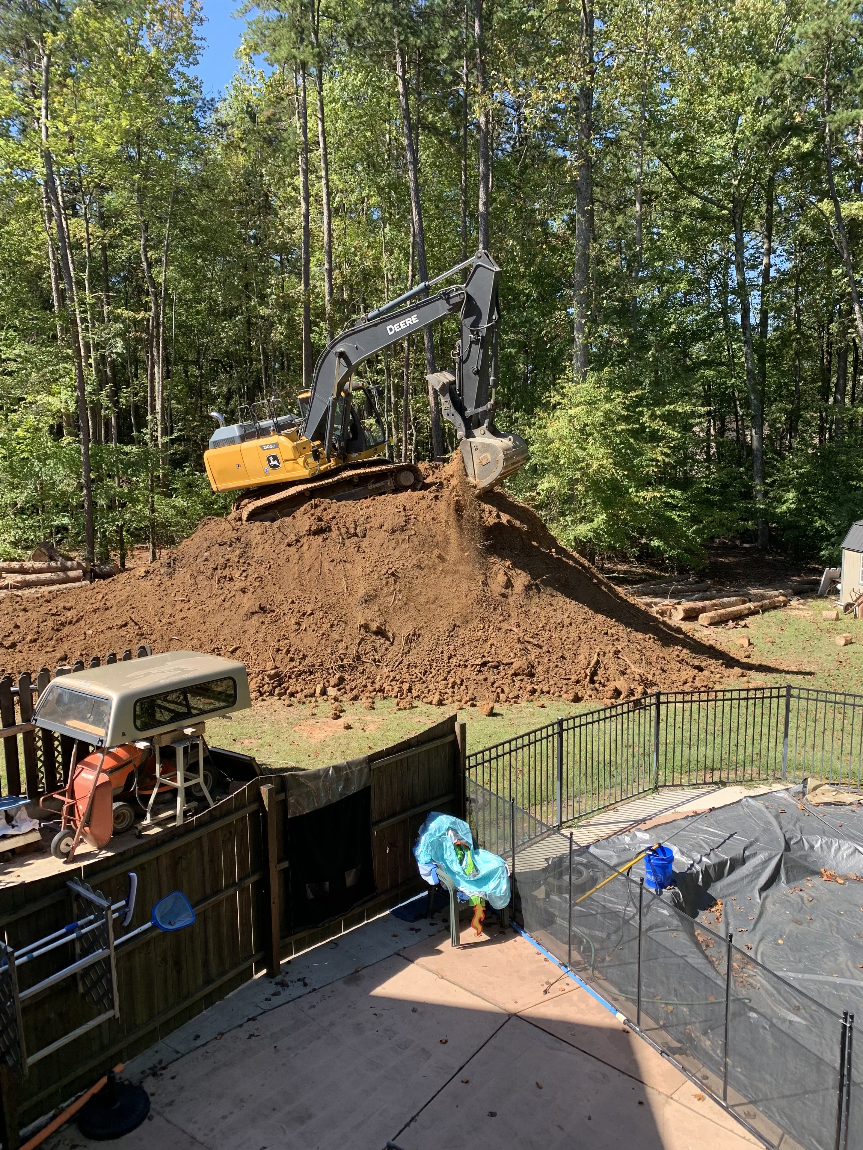 John Deere excavator on top of large dirt mound during residential excavation project