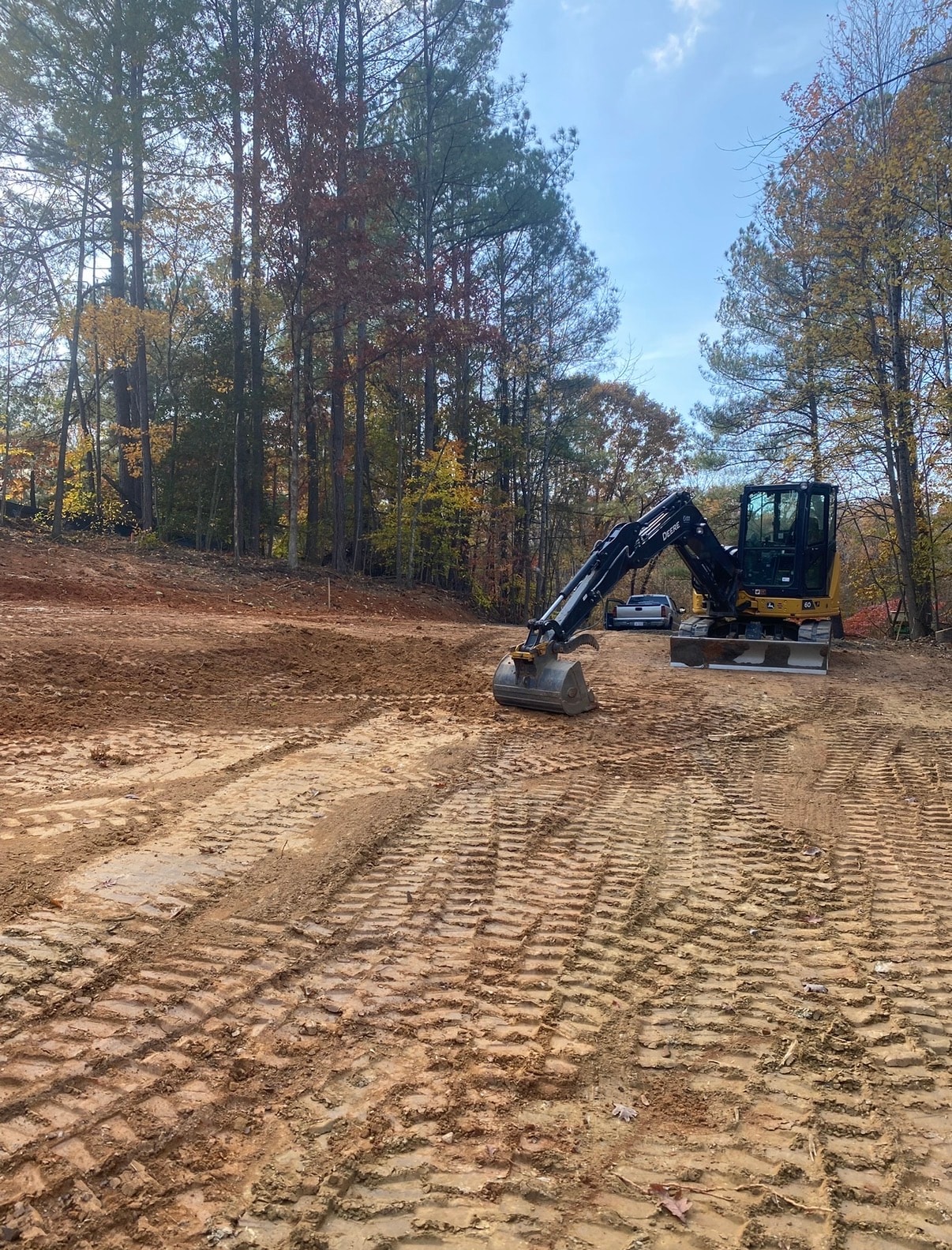 John Deere excavator grading wooded lot