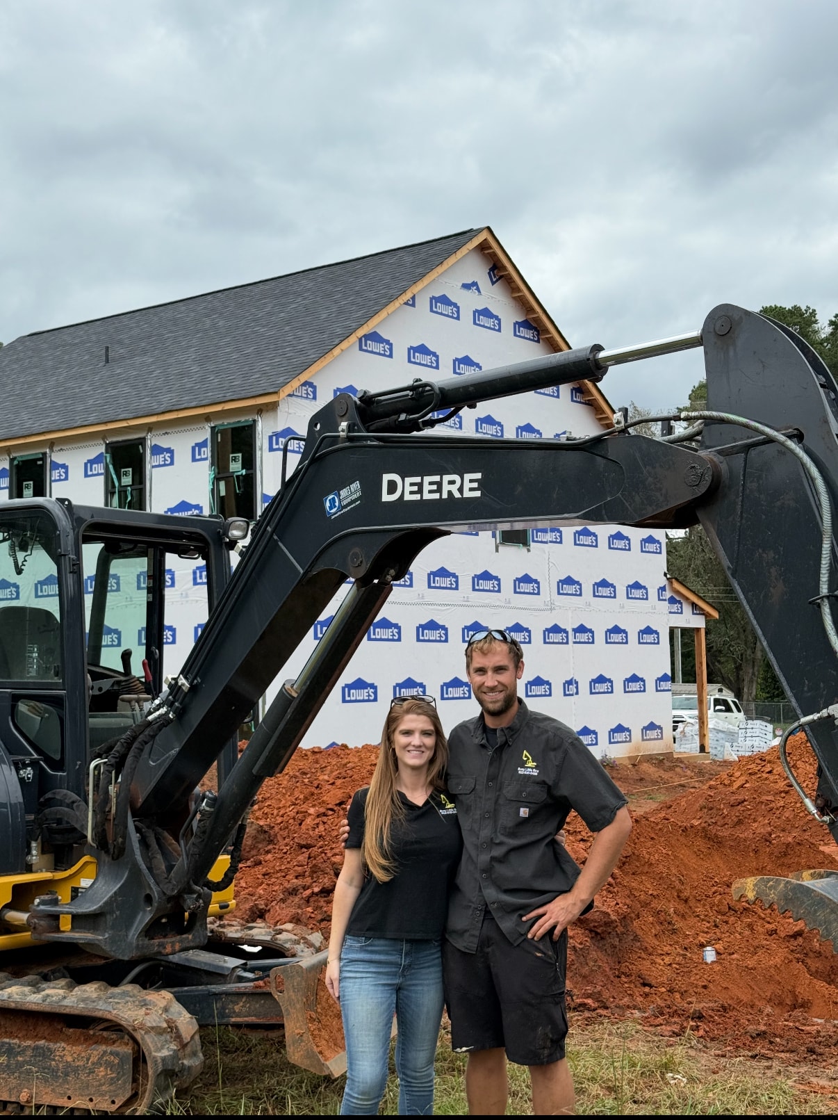 Busy Little Bee LLC owners on job site with John Deere excavator at new home construction